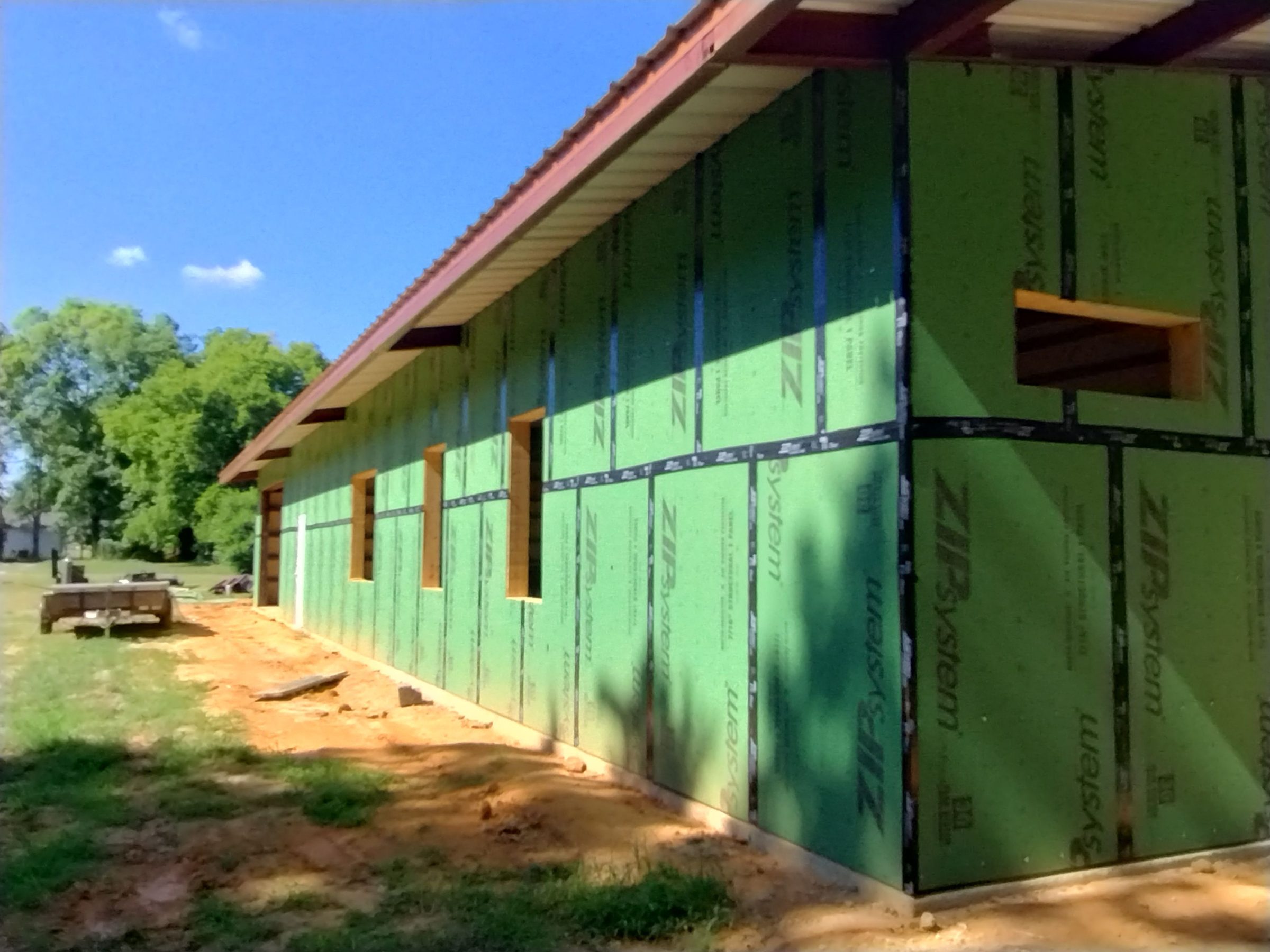Steel building under construction with structural sheathing installed over the frame, ready for exterior panels